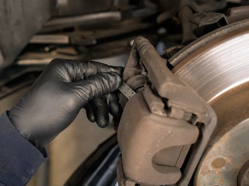 A brake pad measured with a gauge against the rotor