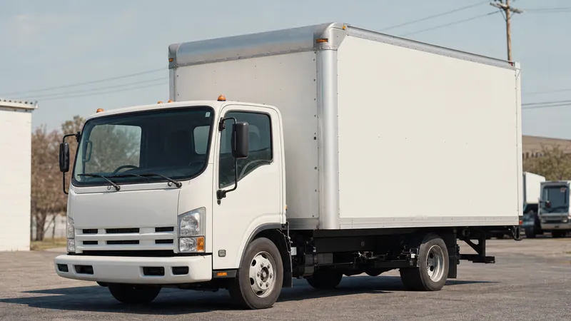 A small box moving truck parked on the rental lot, side view